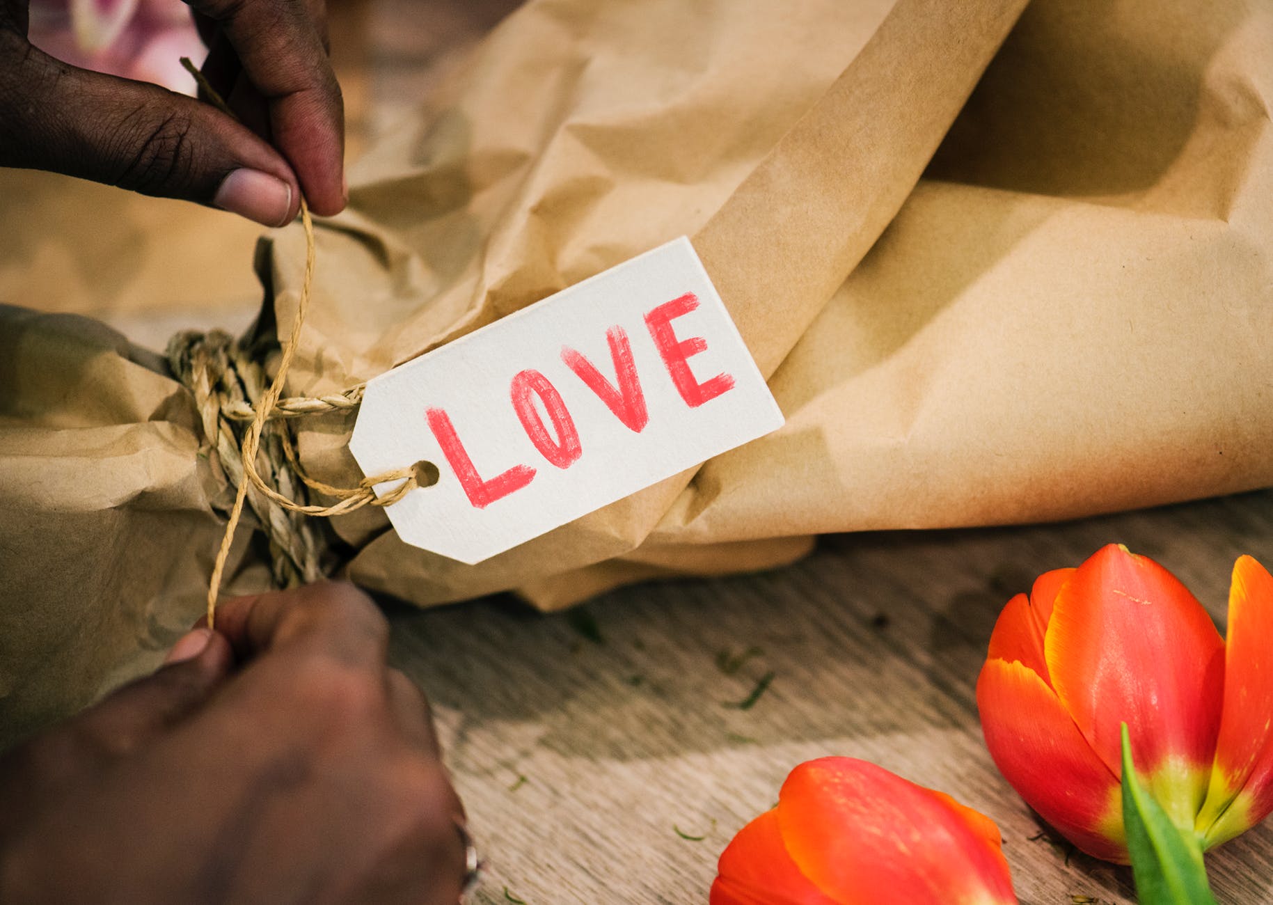 person tying knot on brown paper bag with love tag